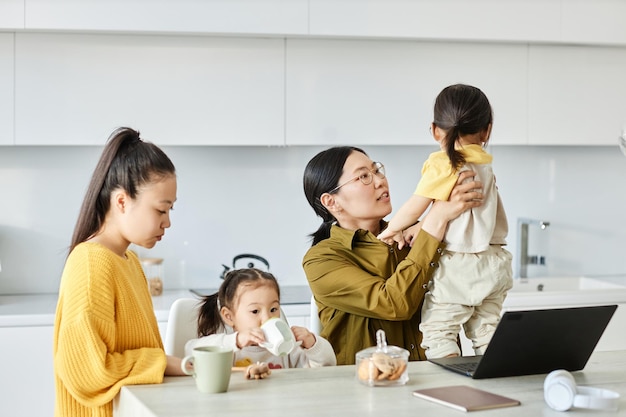 Dos amigos jugando con sus hijos sentados en la cocina de casa