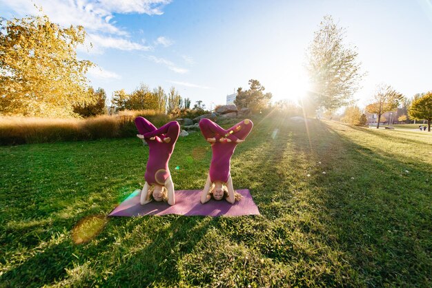 Dos amigos meditando mientras hacen yoga en el parque