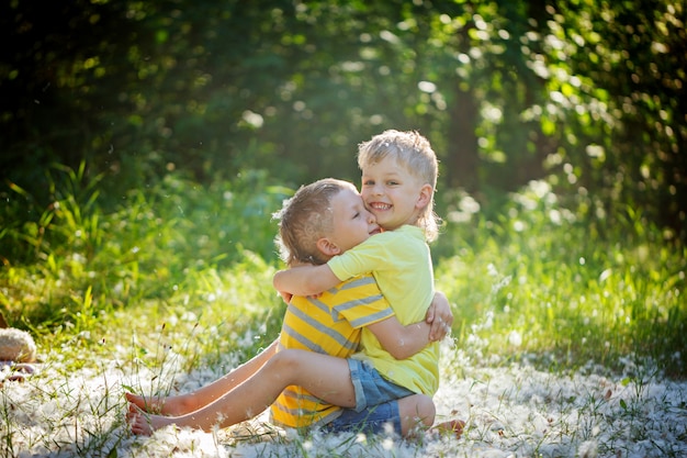 Dos amigos de los niños pequeños se abrazan en el jardín de verano.