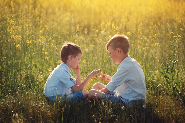 Dos amigos de niños pequeños jugando - piedra, tijeras, juego de papel en el día de verano.