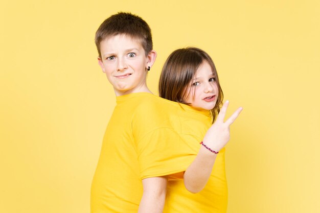 Dos amigos o hermanos que usan la misma camisa de gran tamaño aislados en un fondo amarillo