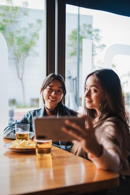 Dos amigos posando mientras se hacen un selfie con el smartphone en un bar