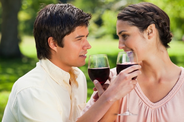 Dos amigos que unen sus brazos mientras sostienen copas de vino