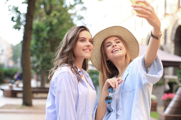 Dos amigos riendo disfrutando juntos el fin de semana y haciendo selfie en el fondo de la ciudad.