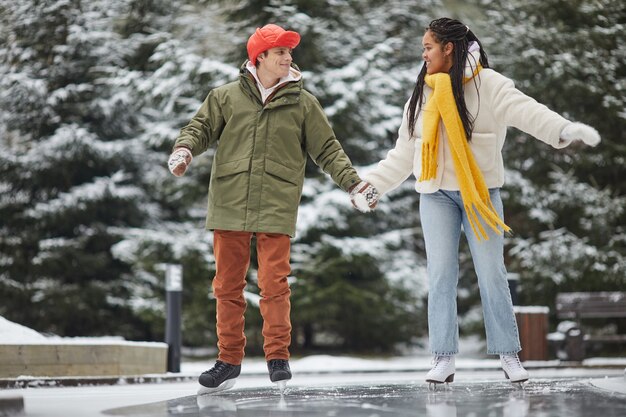 Dos amigos en ropa de abrigo disfrutando del tiempo libre al aire libre patinando en pista de patinaje