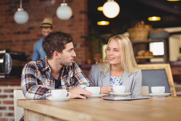 Dos amigos sonrientes hablando y bebiendo café