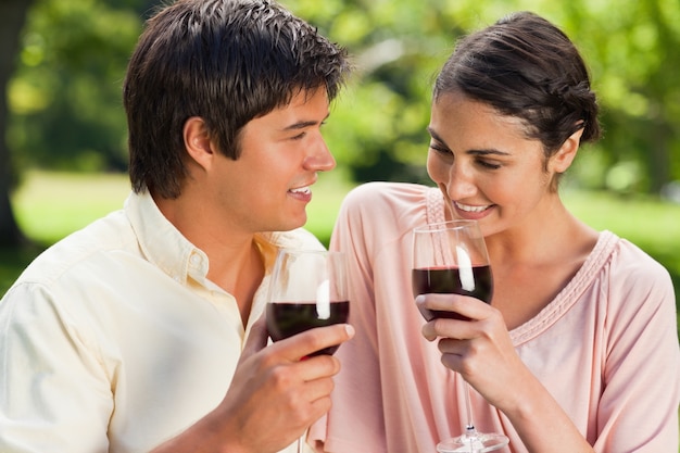 Dos amigos sosteniendo copas de vino en un parque