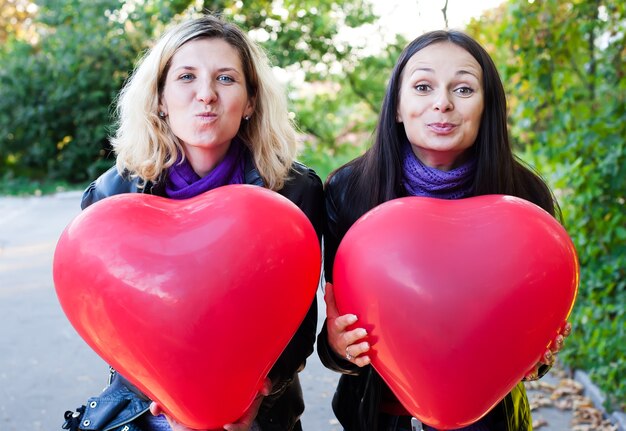 Dos amigos sosteniendo globos en forma de corazón