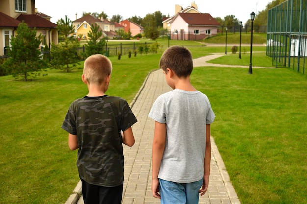 Dos amigos van por el camino en verano. La amistad de los niños.