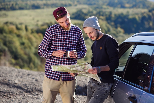 Dos amigos viajeros con gorra de té y mirando el mapa en papel para encontrar la manera correcta.