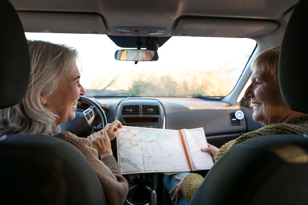 Foto dos ancianas consultando un mapa dentro mientras se embarcan en una aventura