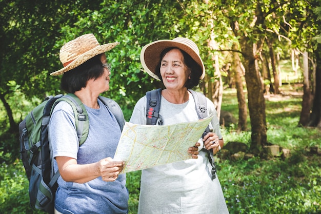 Dos ancianas de excursión Llevando una mochila y llevando un mapa. El concepto de personas mayores que viajan por la naturaleza.