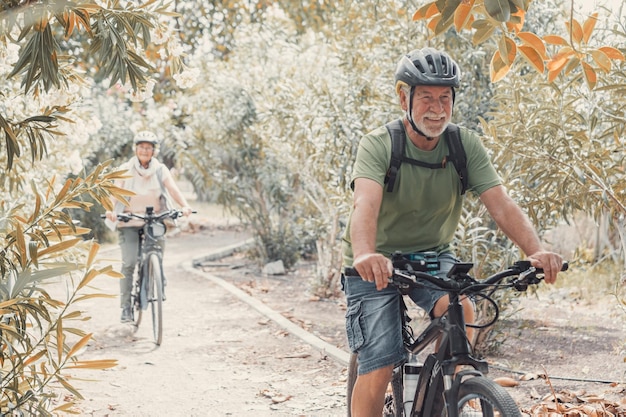 Dos ancianos felices disfrutando y andando en bicicleta juntos para estar en forma y saludables al aire libre Personas mayores activas divirtiéndose entrenando en la naturaleza