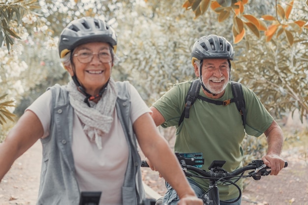 Dos ancianos felices disfrutando y andando en bicicleta juntos para estar en forma y saludables al aire libre Personas mayores activas divirtiéndose entrenando en la naturaleza