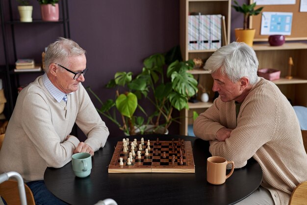 Dos ancianos jugando al ajedrez en la mesa en la casa de retiro