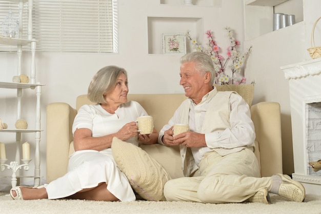 Dos ancianos sentados cerca del sofá con té