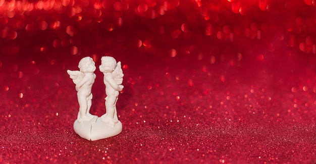 Dos ángeles besos sobre fondo rojo con bokeh Cupido de San Valentín, espacio de copia
