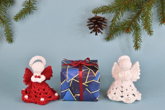 Foto dos ángeles de ganchillo están al lado de un regalo de año nuevo envuelto