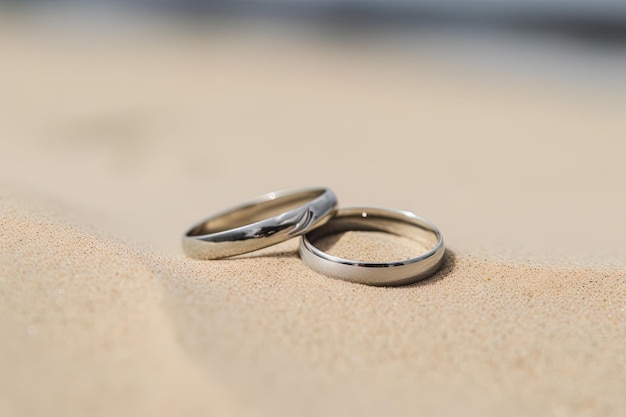 Dos anillos de boda en la arena en el fondo de una playa y un mar