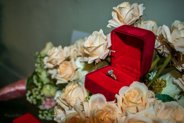 Dos anillos de boda en una caja decorativa roja, en muchas flores.