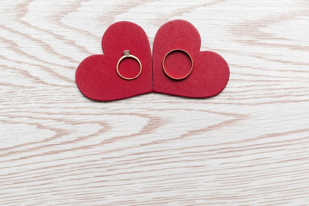 Dos anillos de boda en corazones rojos sobre fondo de madera con espacio de copia Día de San Valentín