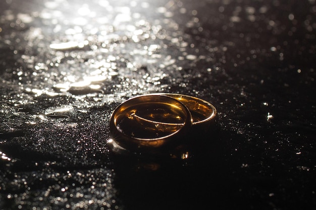 Dos anillos de boda dorados sobre fondo negro