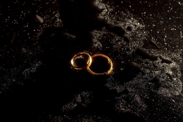 Dos anillos de boda dorados sobre fondo negro