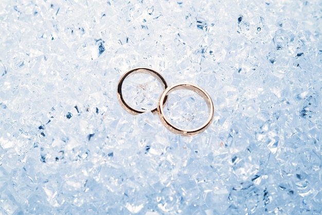 Dos anillos de boda dorados sobre hielo.