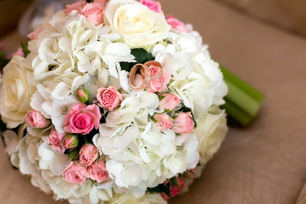 Dos anillos de boda en un ramo de rosas rojas y blancas.