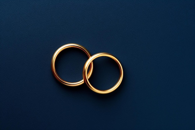 Dos anillos de bodas dorados sobre un fondo azul oscuro