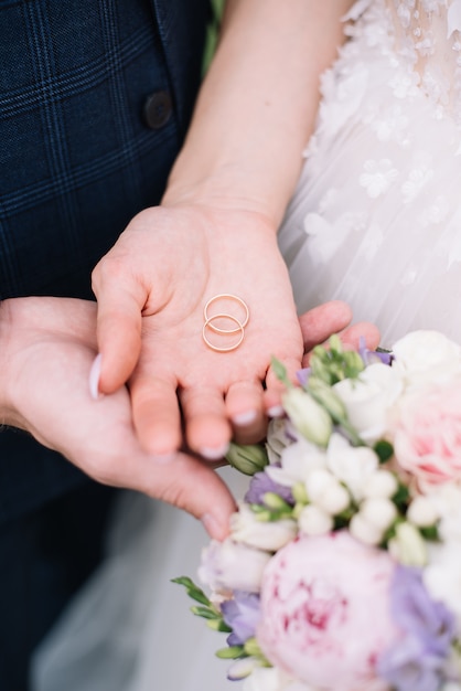 Dos anillos de bodas en las manos de los recién casados anillos de bodas de plata anillos de bodas de metales preciosos en las manos de un hombre y una mujer ceremonia de boda.