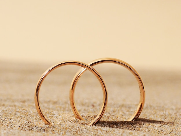 Dos anillos de bodas de oro en la arena, una luna de miel.