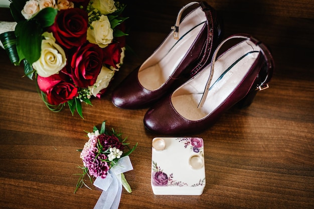 Dos anillos de bodas de oro en una caja sobre un fondo marrón de madera Zapatos de mujer un ramo de novia y un boutonniereVista superior Anillos de bodas de la novia y el novio Compromiso