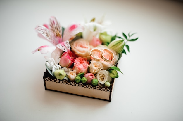 Dos anillos de bodas de oro dispuestos en la bonita composición de flores