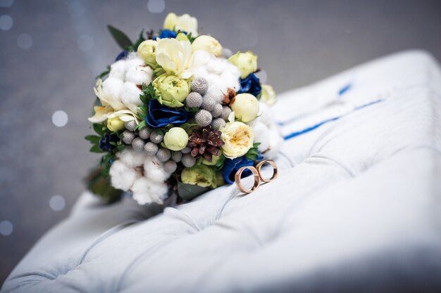 Dos anillos de bodas de oro y un hermoso ramo azul y blanco