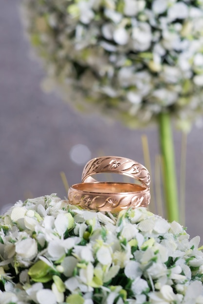 Dos anillos de bodas de oro sobre flores verdes