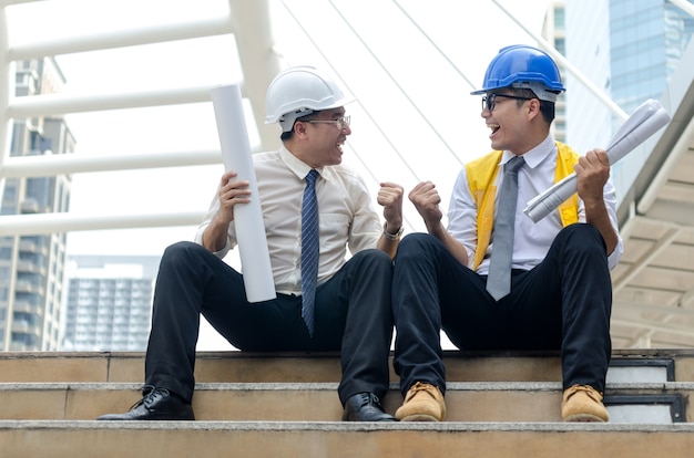 Dos arquitectos asiáticos manteniendo las manos con momento feliz.