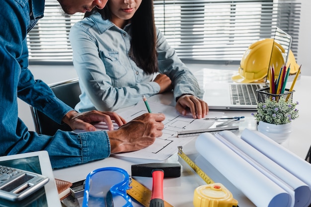 Dos arquitectos trabajando y discutiendo datos y computadora portátil en proyecto arquitectónico en la oficina