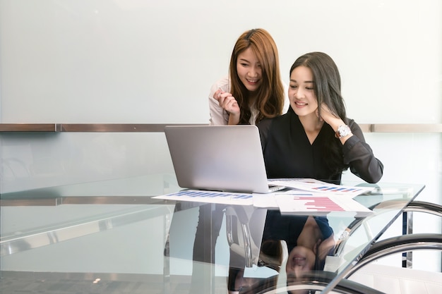 Dos asiáticos jóvenes empresaria sentado y usando la tecnología portátil