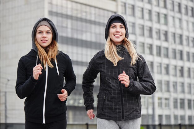 Dos atletas de chicas corriendo por la calle de la ciudad. Novias en los deportes