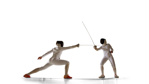 Dos atletas de esgrima luchan aisladas en blanco