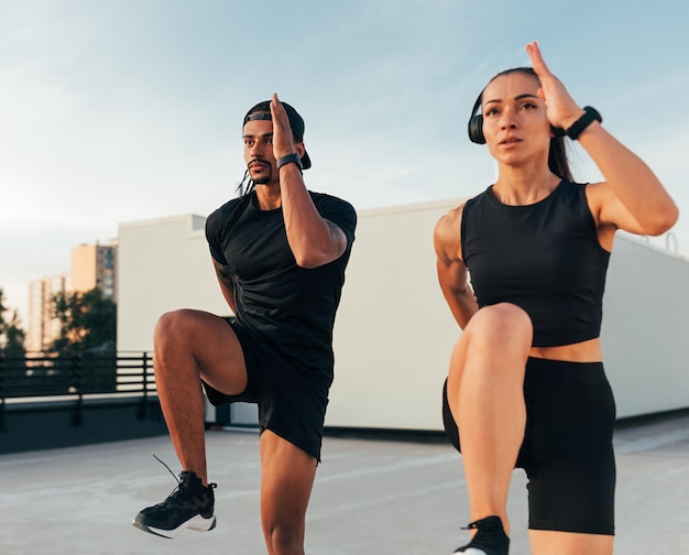 Dos atletas en ropa deportiva negra practicando juntos en el techo