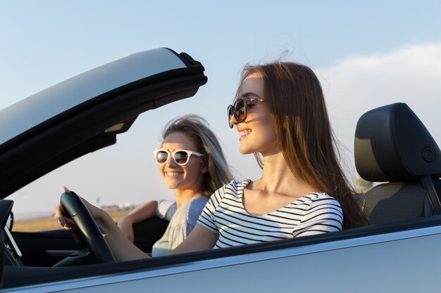 Dos atractivas mujeres jóvenes en un coche descapotable