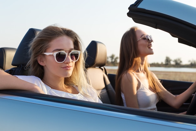 Dos atractivas mujeres jóvenes en un coche descapotable