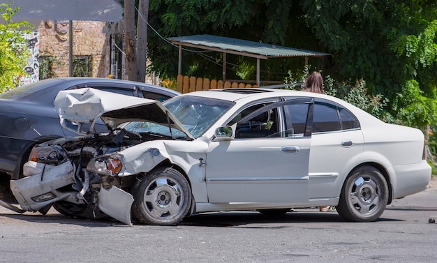 Dos autos en la carretera después de la colisión Coche blanco dañado en la carretera después del accidente