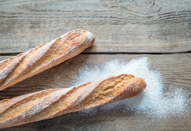 Dos baguettes de trigo integral en el fondo de madera