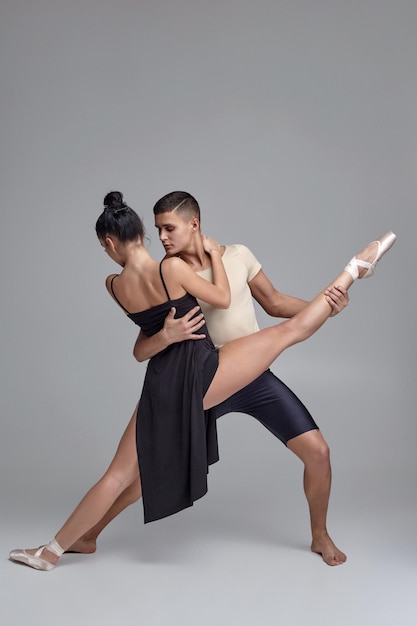 Dos bailarines de ballet moderno atléticos están posando sobre un fondo gris de estudio.