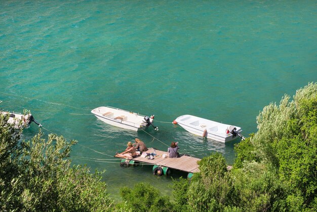 Dos barcos en el mar y tres personas en el muelle