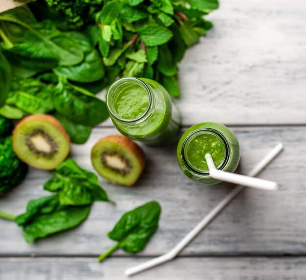 Dos batidos con verduras, aguacate, manzana, kiwi sobre un fondo de madera. nutrición deportiva