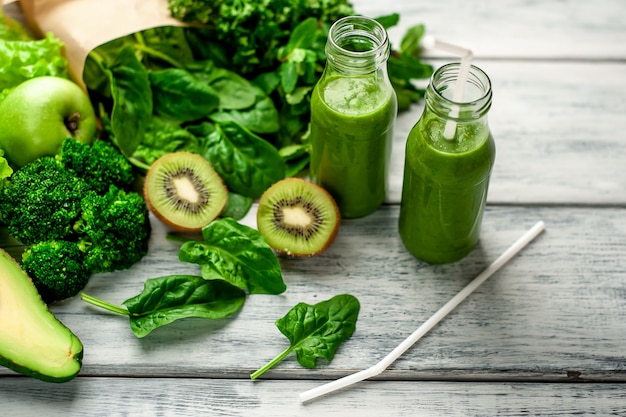 Dos batidos con verduras, aguacate, manzana, kiwi sobre un fondo de madera. nutrición deportiva